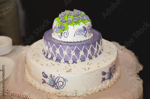Three-tiered purple wedding cake with green roses