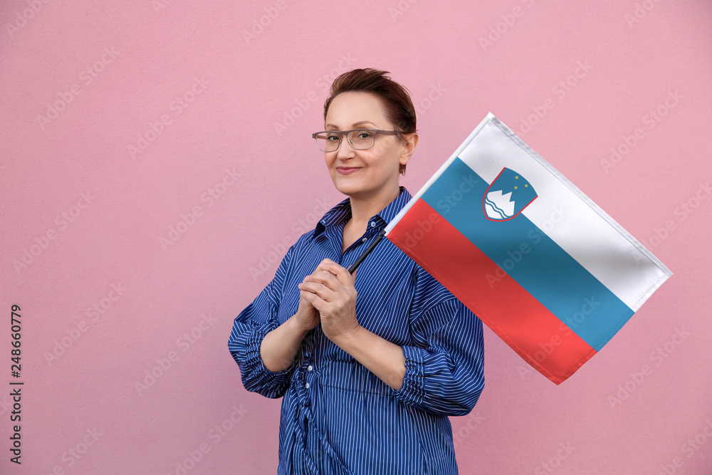 Slovenia flag. Woman holding Slovenian flag. Nice portrait of middle aged  lady 40 50 years old holding a large flag over pink wall background on the  street outdoors. Stock Photo | Adobe Stock
