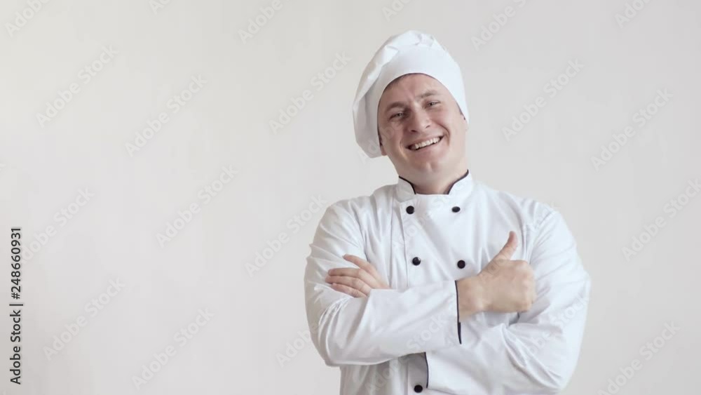 White-skinned chef man in chef's clothes, waist-deep in a bright room, crossing his arms on his chest, looking forward, looks away and smiling at the camera and shows the class White-skinned chef man in chef's clothes, waist-deep in a bright room, crossing his arms on his chest, looking forward, looks away and smiling at the camera and shows the class