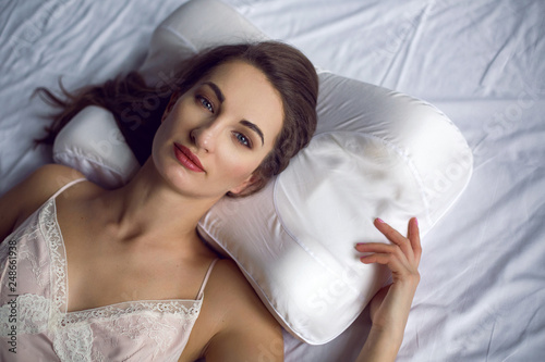 young woman in a nightgown lying in a white bed