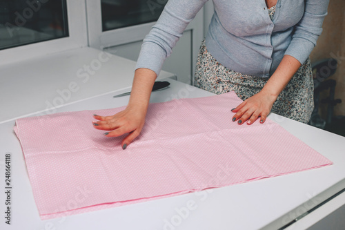 Close up. hands woman Tailor working cutting a roll of fabric on which she has marked out the pattern of the garment