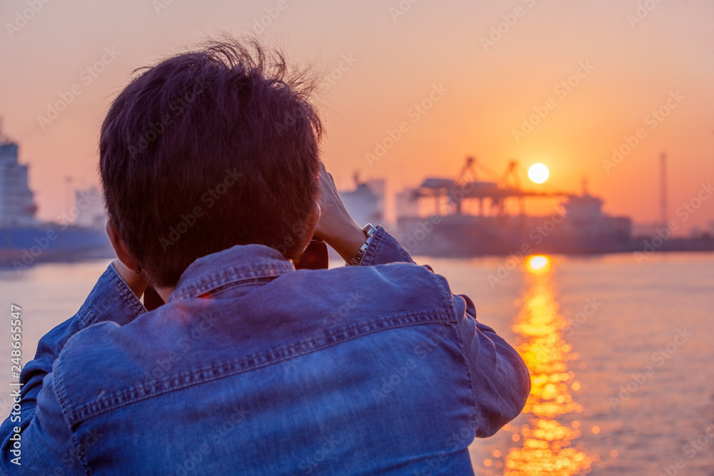 Fototapeta premium Male photographer taking photo of riverside sunset.