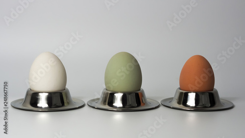 three nature colored eggs in a egg cup photo