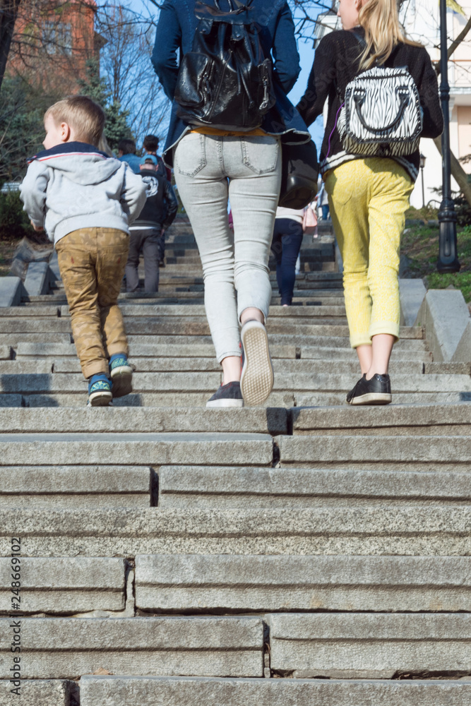 Many walking legs. Legs of children and mothers climb the stairs in the summer.