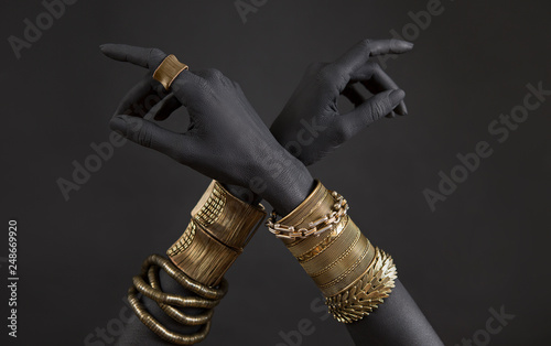 Black woman's hands with gold jewelry. Oriental Bracelets on a black painted hand.