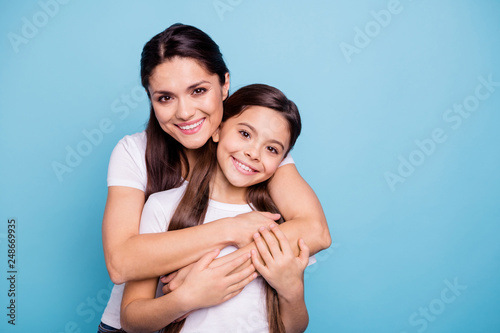 Close up photo amazing pretty two people brown haired mum mom small little daughter stand hugging piggy back lovely free time rejoice wearing white t-shirts isolated on bright blue background