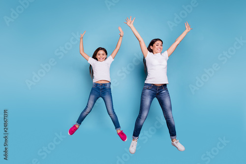 Full length body size view of two nice lovely attractive charming cheerful funny slim people in white t-shirt jeans denim raising hands up party isolated over blue pastel background