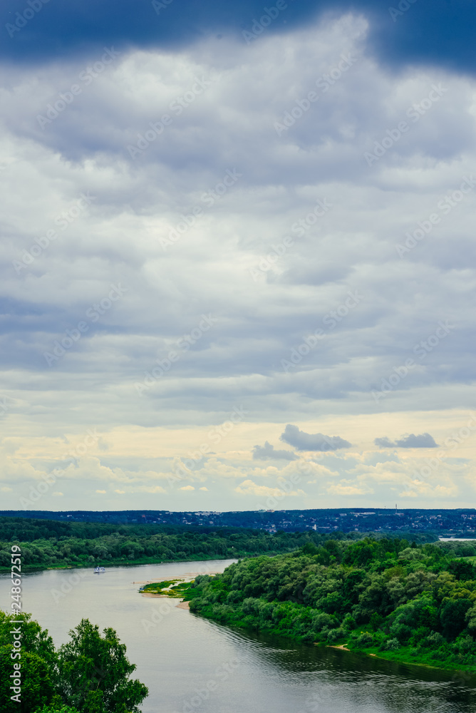Fototapeta premium River and sky before the storm. Ship, steamer on the horizon. Summer river in cloudy day. Coastal area, beach, lake bank. Amazing summer landscape with meadow, trees for nature calendar, poster, print
