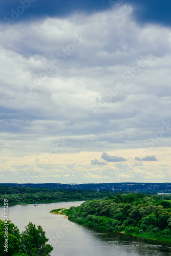 River and sky before the storm. Ship, steamer on the horizon. Summer river in cloudy day. Coastal area, beach, lake bank. Amazing summer landscape with meadow, trees for nature calendar, poster, print