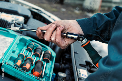 Mechanic repairs car. Wrench in male hand. Car service, engine repair, car repair shop. Hands of car mechanic in auto repair service.