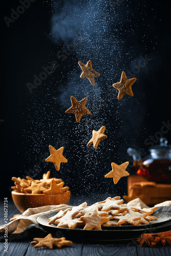 Falling stars shaped cookies with powdered sugar. Vertical composition on a dark background