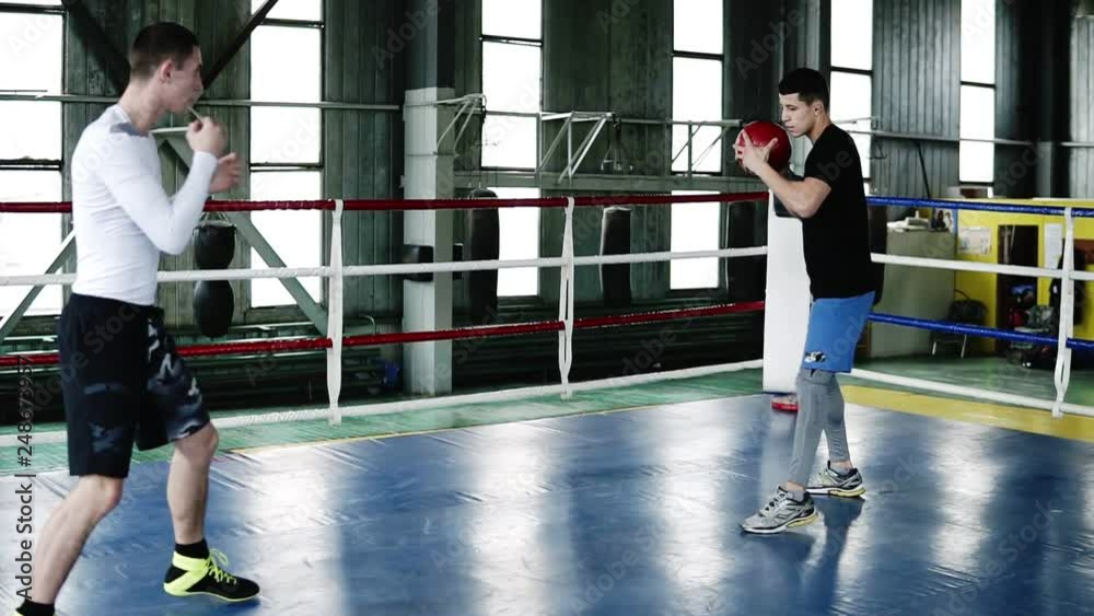 Caucasian men throwing medicine ball to each other while doing punces