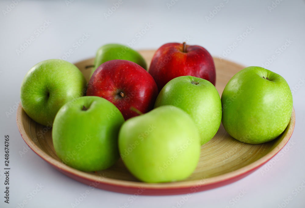 Green and red apple lies on a white table Green and red apple lies on a white table