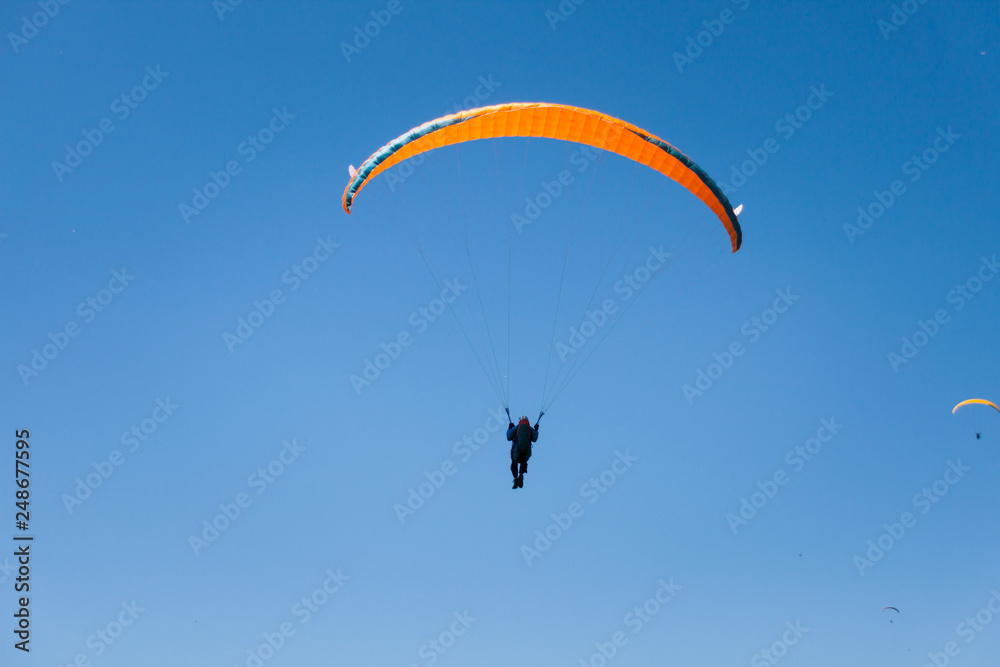 Paraglider Flying in Blue Sky on a Sunny Summer Day Paraglider Flying in Blue Sky on a Sunny Summer Day