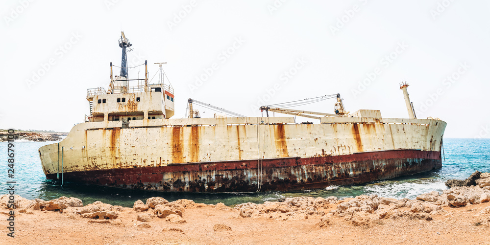 Fototapeta premium Old damaged rusty transportation ship after crash on the coastline.