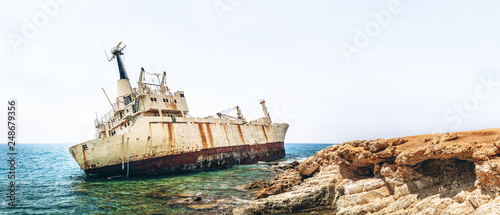 Old damaged rusty transportation ship after crash on the coastline.