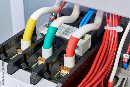 Three cables or wires are connected to a powerful electrical contactor. The magnetic starter is fixed in the electrical Cabinet. Reliable, modern connection. To the right a bundle of flexible wires.