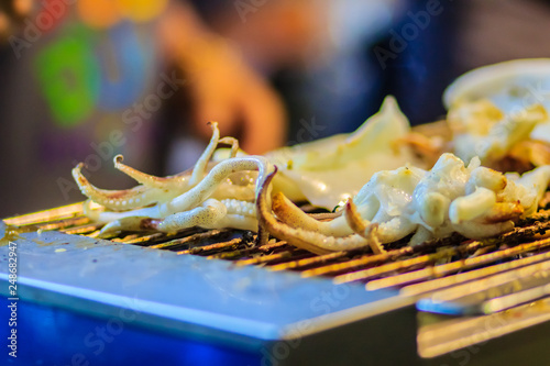 Closeup of Grilling squid, the Exotic Street foods at night market in Thailand. The squid grilled on fire for seafood buffet in the restaurant.