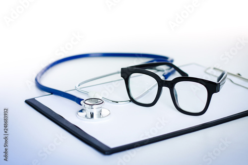 The doctor's glasses are placed on the writing board and have medical headphones.