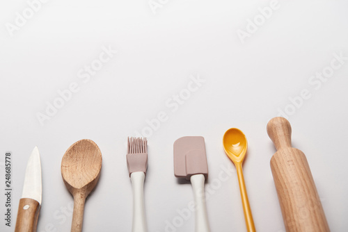 cooking utensils arranged in line on grey background with copy space © LIGHTFIELD STUDIOS