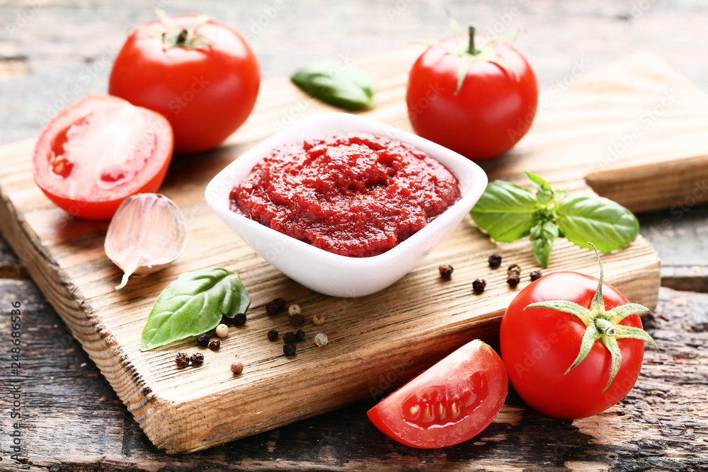 Ketchup in bowl with basil leafs and pepper on wooden table Ketchup in bowl with basil leafs and pepper on wooden table