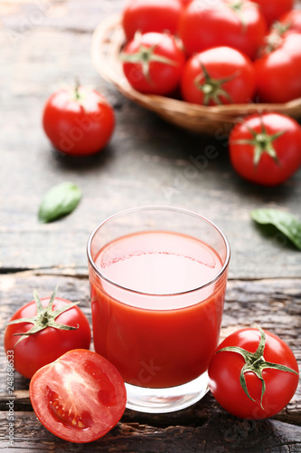 Tomato juice in glass on grey wooden table