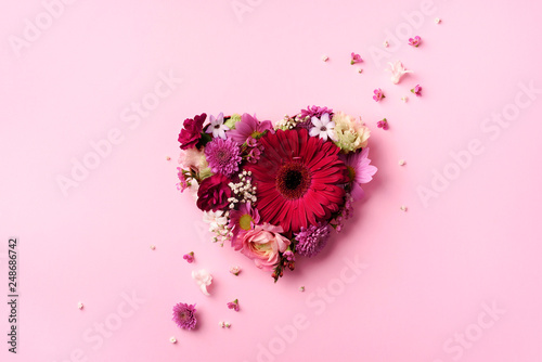 Fototapeta Naklejka Na Ścianę i Meble -  Heart shape made of spring flowers on pink punchy pastel background. Top view, flat lay. Summer concept. Valentine's day. Creative layout.