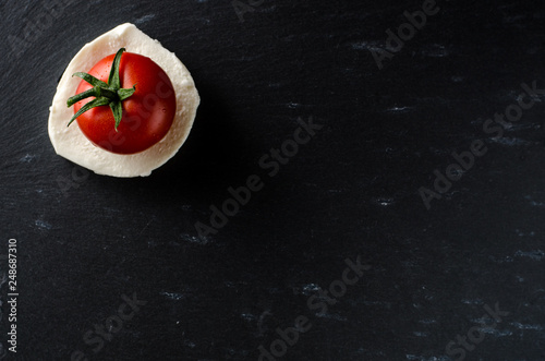 Mozzarella and tomato on black cutboard photo