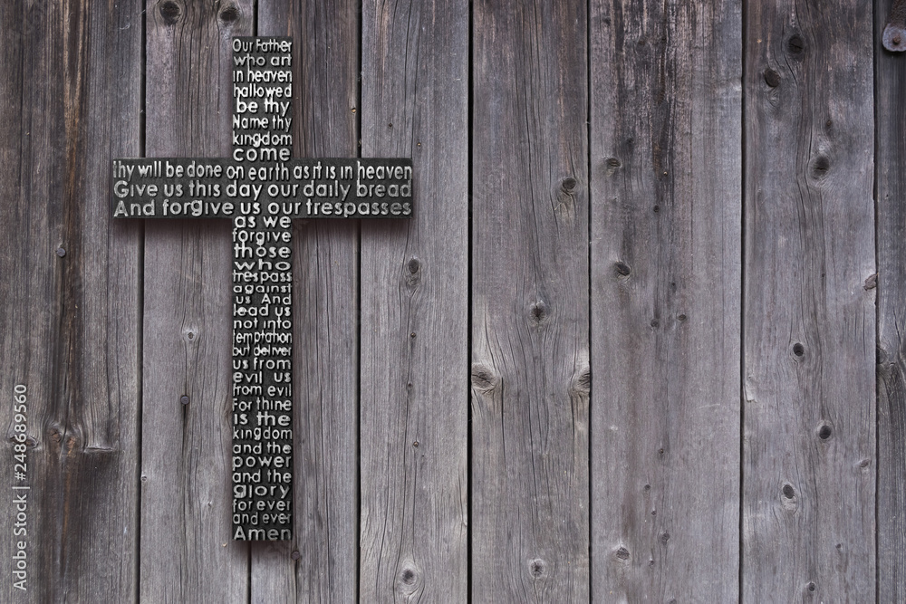 Black wooden cross with the Lord's prayer on the old  dark brown wooden  plank background