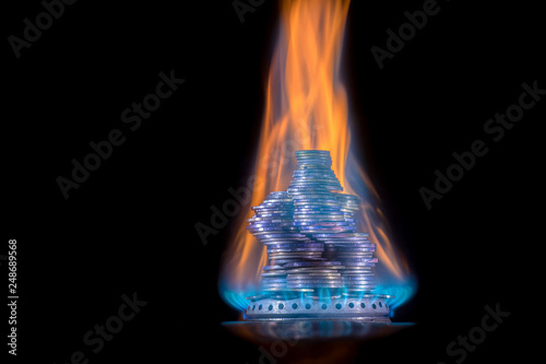 Money on fire. The concept of high prices for natural gas. Blue flame of burning natural gas from a gas stove with Ukrainian coins.
