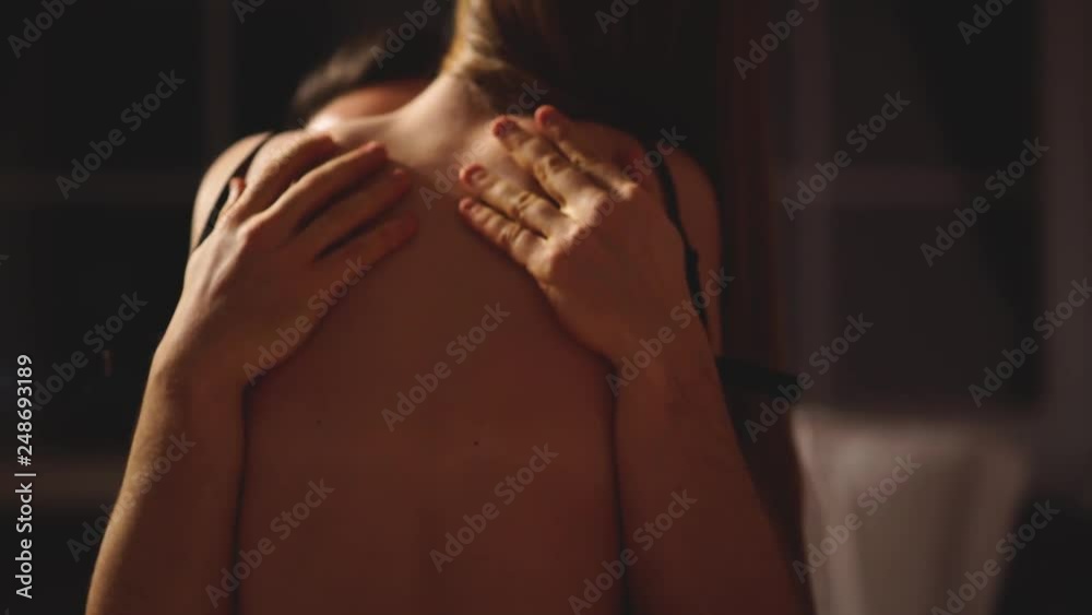 A man is stroking the girls bare back. Two lovers in an intimate setting. Seductive and sensual man and woman touch each other tender. Slow motion.