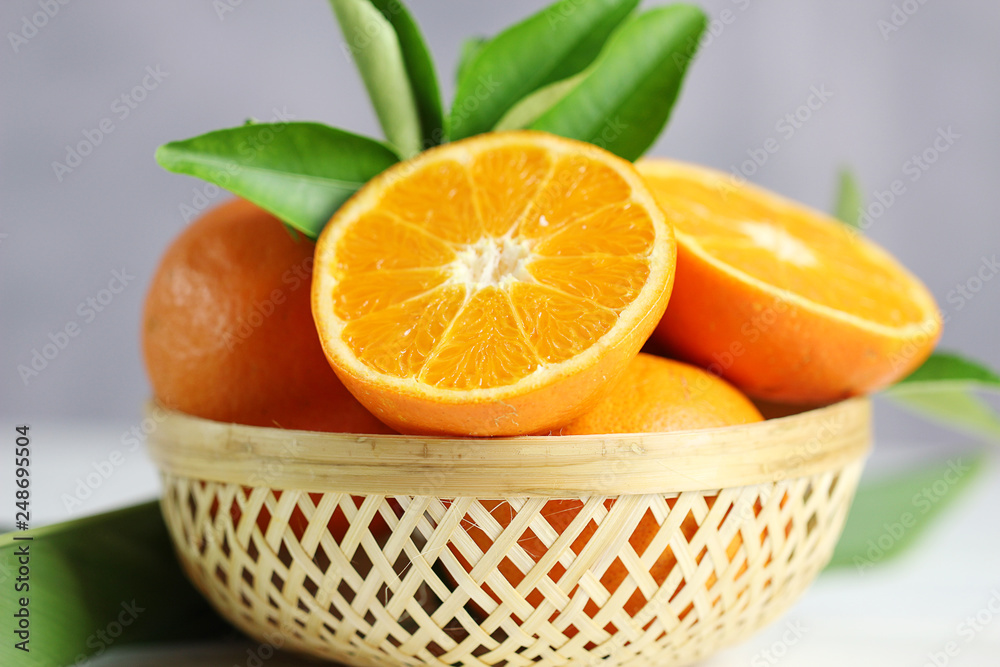 Fresh oranges fruit in basket on white table background.