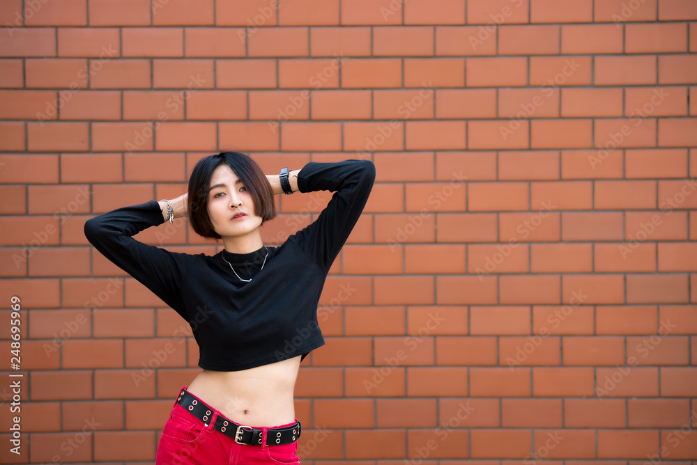Fototapeta premium Portrait of beautiful asian chic girl pose for take a picture on wall background,Lifestyle of teen thailand people,Modern woman happy concept,Punk rock style