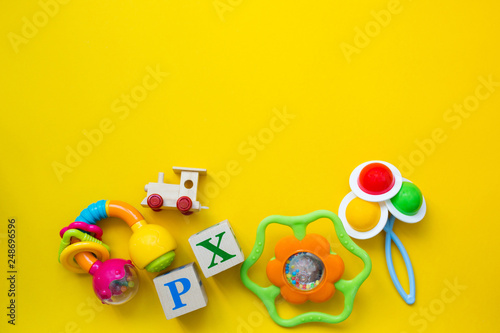 Kid's toys for a newborn baby. Various children's items for the game on a yellow background. Copy space and top view.