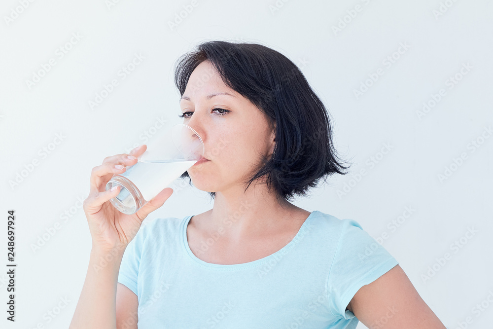 Happy beautiful young woman drinking water. Smiling caucasian female model holding transparent glass in her hand. Closeup. Focus on the arm Happy beautiful young woman drinking water. Smiling caucasian female model holding transparent glass in her hand. Closeup. Focus on the arm