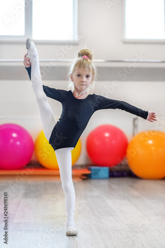 Girl kid is engaged in stretching in the dance class. The concept of sports, education, hobbies, training and dance