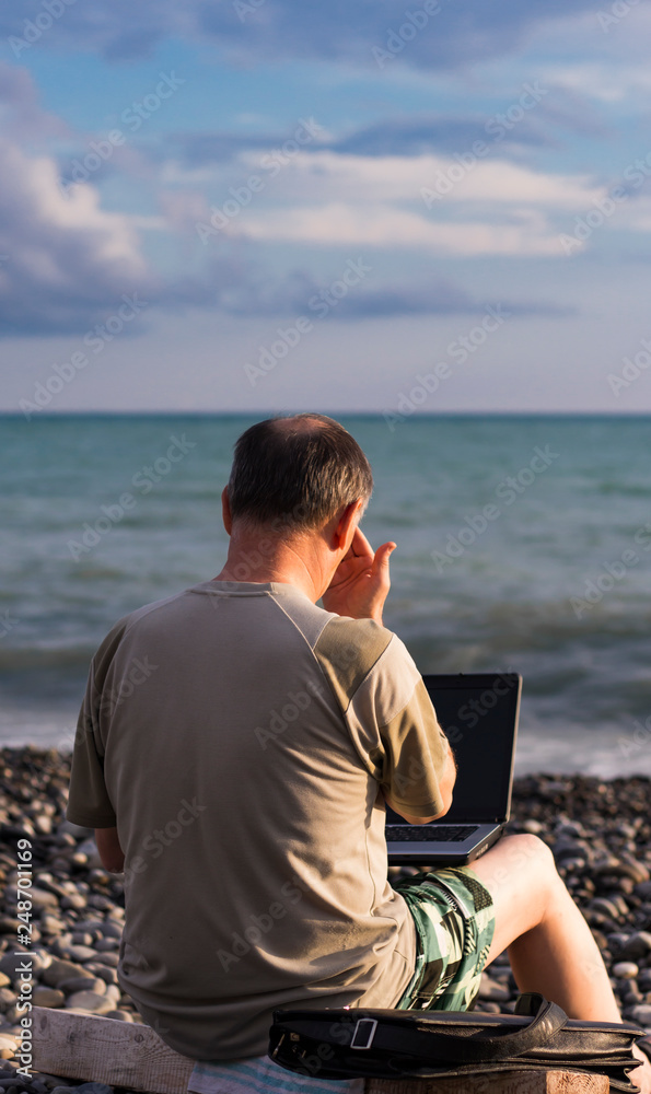 a man working on the beach for a laptop