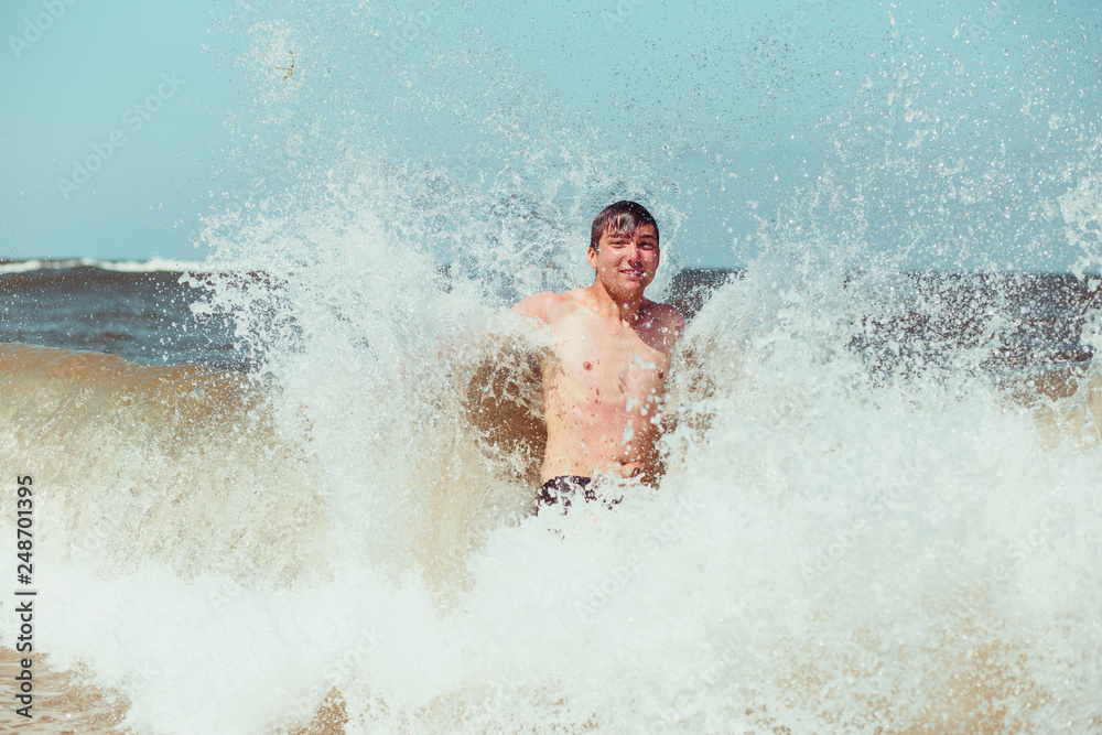 Young man enjoying the high waves in the sea during a summer vacations
