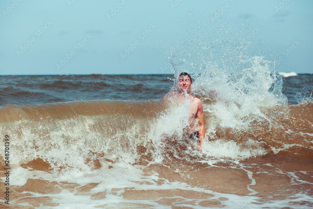 Young man enjoying the high waves in the sea during a summer vacations