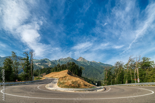 Steep turn on asphalt mountain road. Mountain landscape, sunny morning.