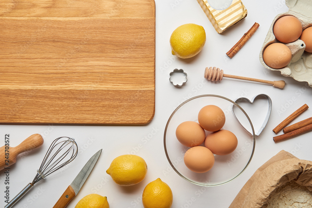 top view of empty wooden cutting board and bakery ingredients on grey background top view of empty wooden cutting board and bakery ingredients on grey background