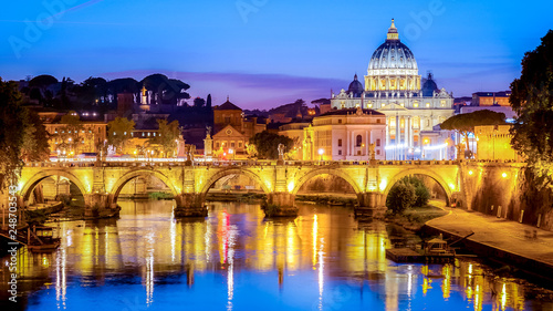 The dome of Saint Peters Basilica and Vatican City at dusk. Sant'Angelo Bridge over the Tiber River. Rome, Italy