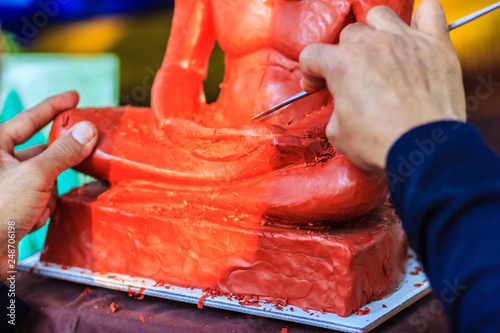 Sculptor carving the clay monk image. Thai sculpture artist molding and carving clay for making famous monk image. The craftsman concentrate to use the tools carving for art work