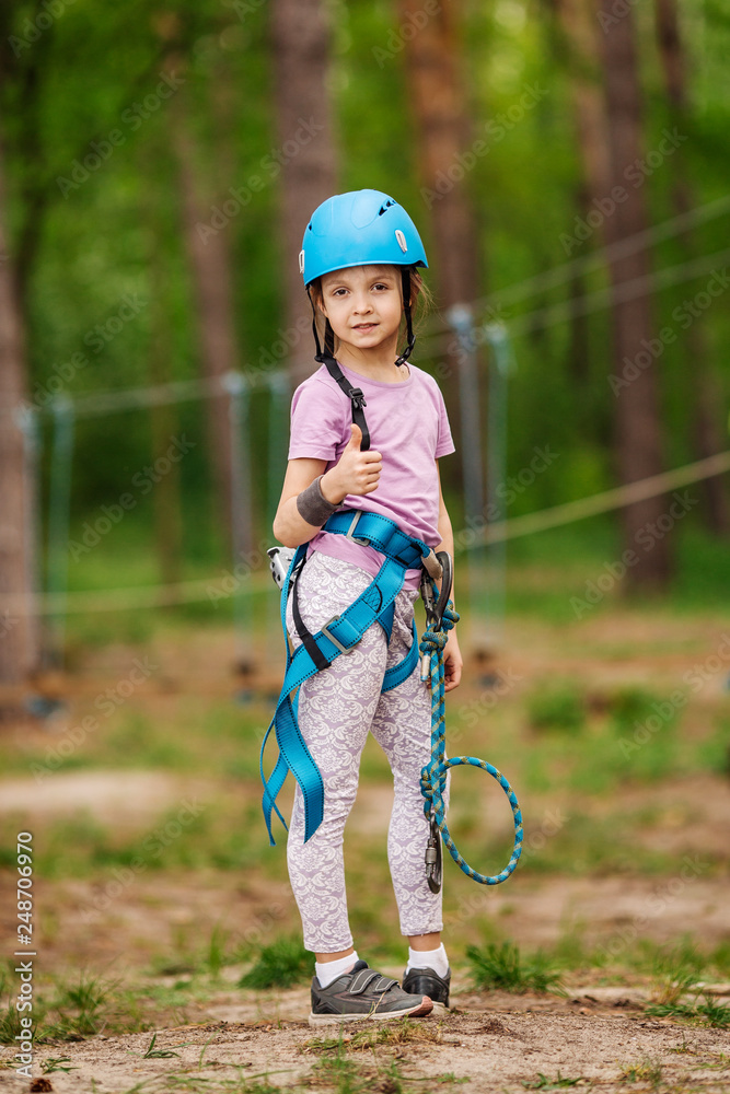 baby girl with climbing gear in an adventure park are engaged in rock climbing or pass obstacles on the rope road. baby girl with climbing gear in an adventure park are engaged in rock climbing or pass obstacles on the rope road.