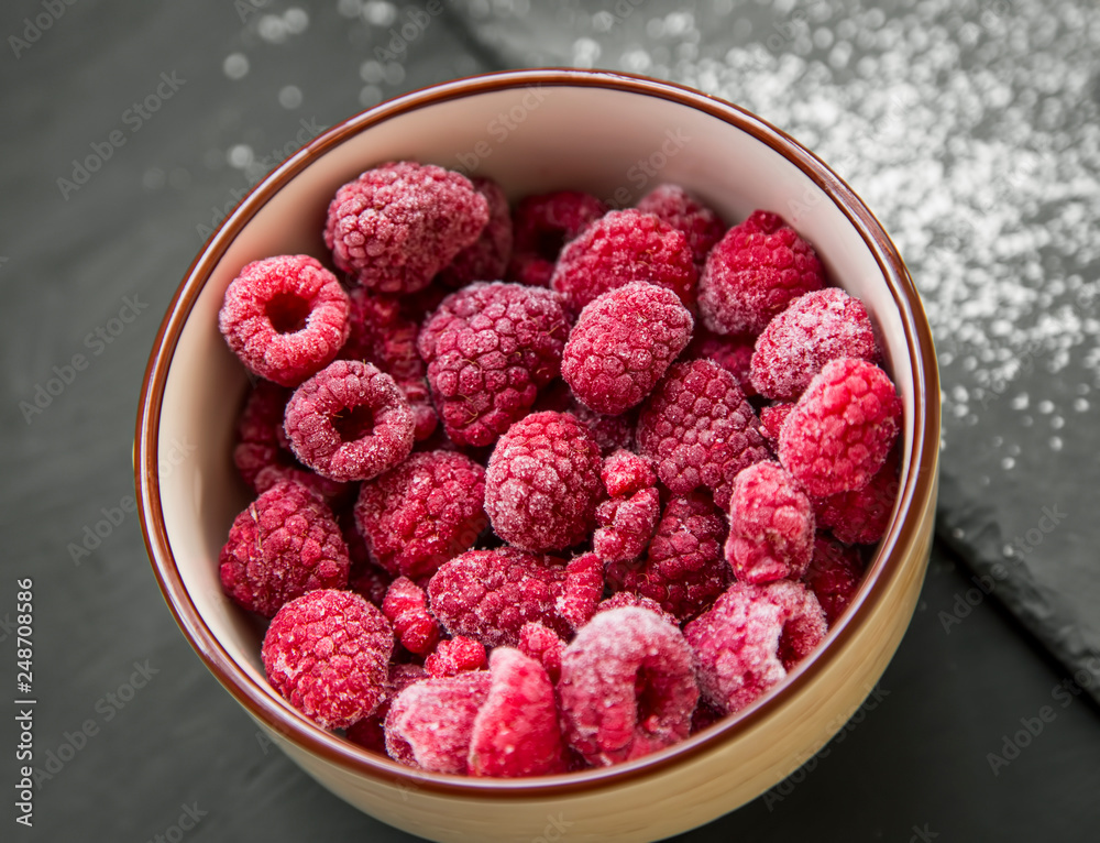Bowl of fresh frozen raspberries fruit, closeup top view Bowl of fresh frozen raspberries fruit, closeup top view