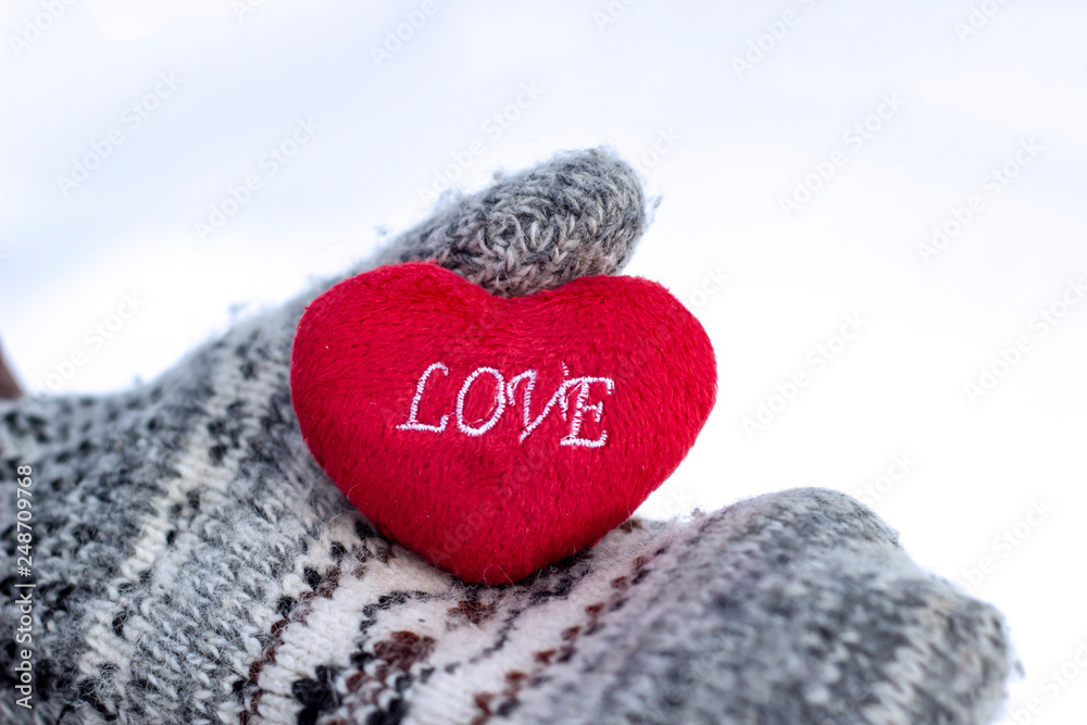 The girl in mittens holding a heart with the inscription LOVE