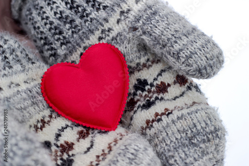 Woman holding a red heart in mittens in winter weather