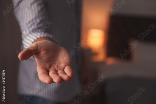 Man offering helping hand on blurred background, closeup. Space for text
