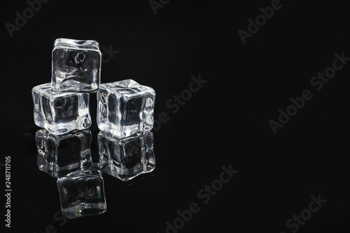 Pile of crystal clear ice cubes on black background. Space for text