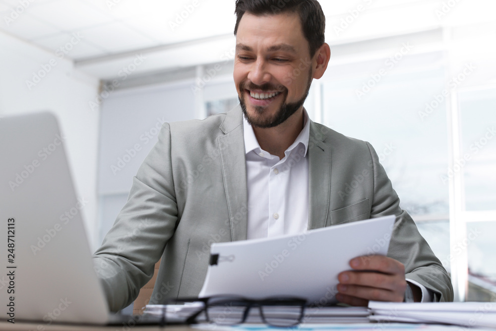 Businessman working with laptop and documents at table in office Businessman working with laptop and documents at table in office